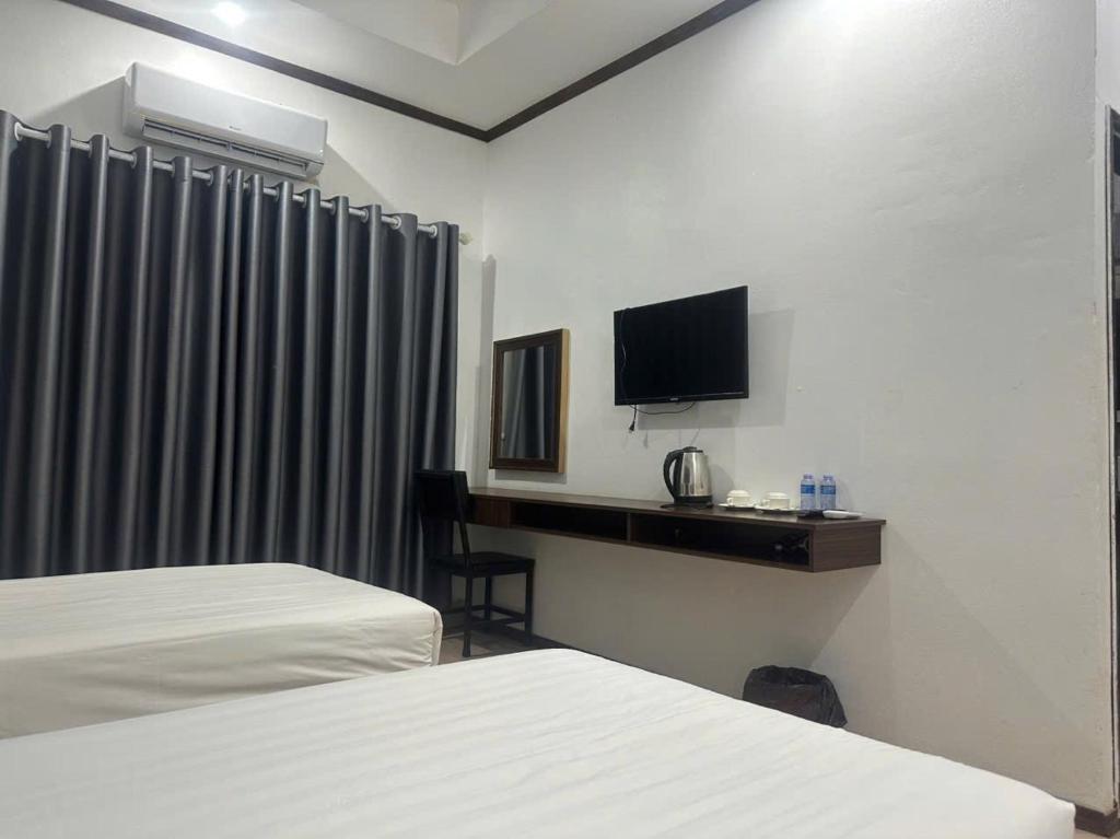une chambre d'hôtel avec deux lits et un bureau avec une télévision dans l'établissement Avenue Hotel VangVieng, à Vang Vieng