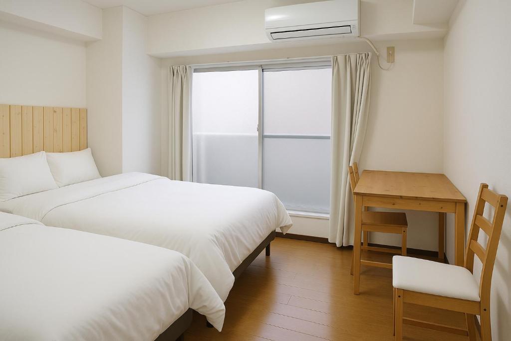 a bedroom with two beds and a desk and a window at Spacious Apartment near Dotonbori Namba Walk to Nipponbashi 801 in Osaka