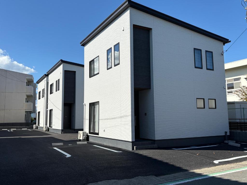Quelques bâtiments blancs dans un parking dans l'établissement 縁-Takasaki, à Takasaki