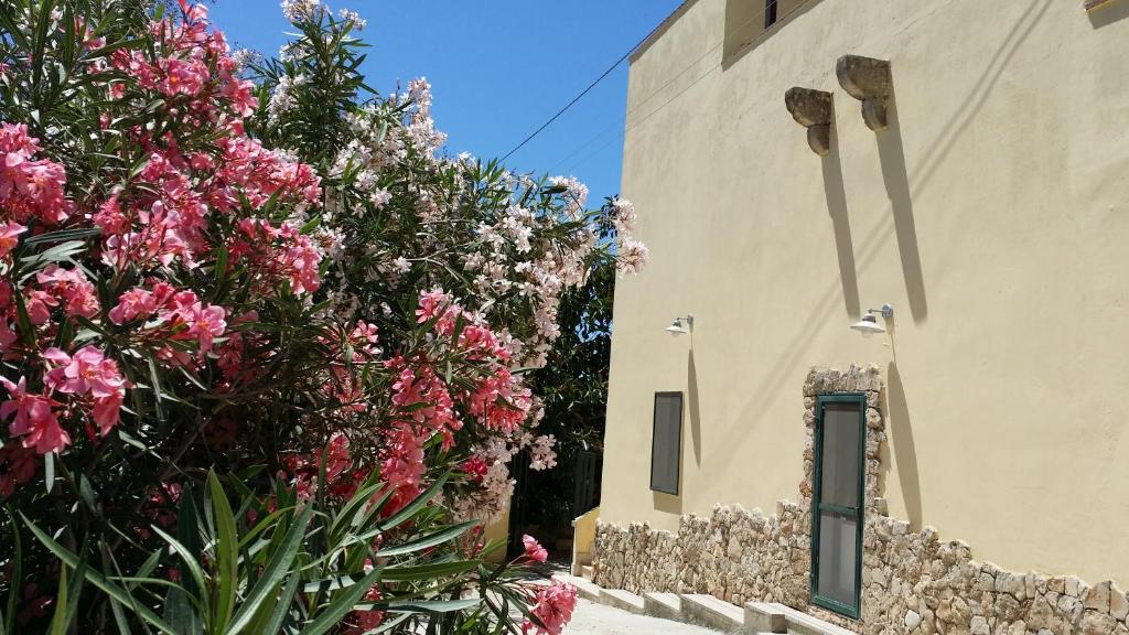 un edificio con fiori rosa accanto a un muro di Agriturismo Tenuta La Siesta a Gallipoli