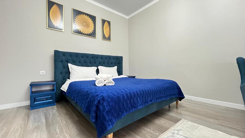 a bed with a blue comforter and two white bows at Athletic City, 1-Room Apartments in Taldykolʼ