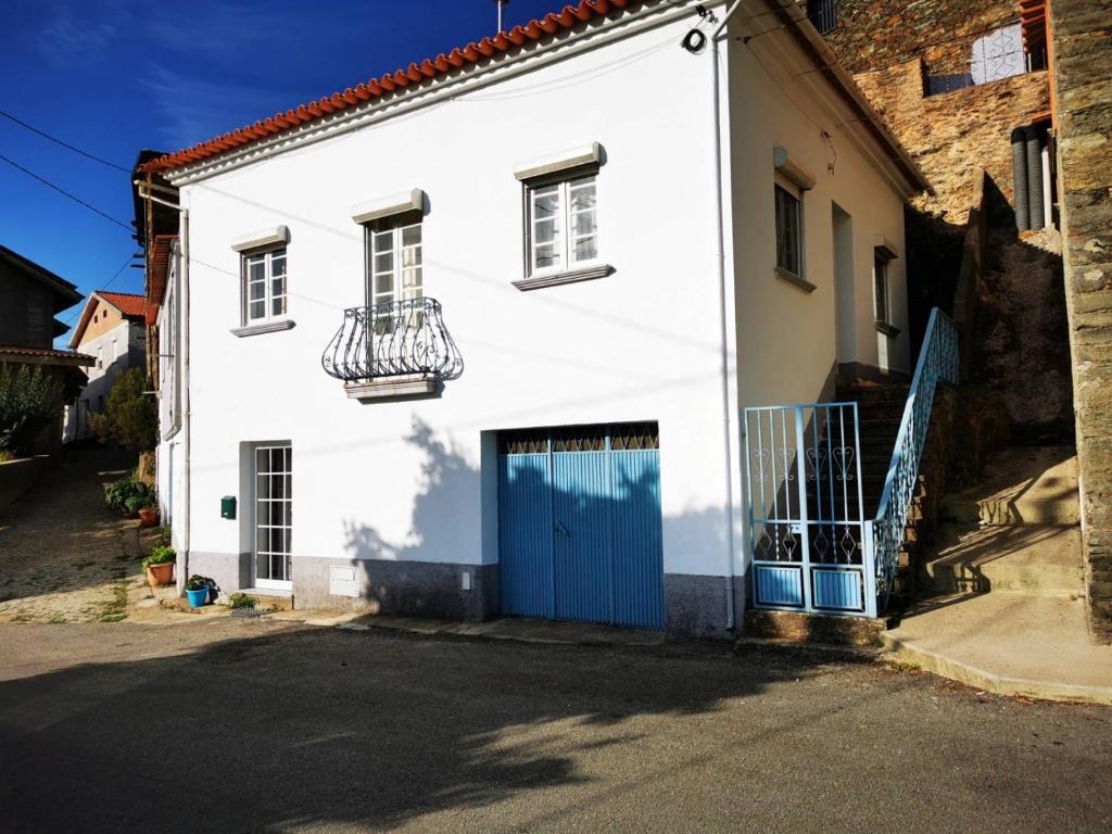 a white house with a blue door and a balcony at O Ninho in Cepos