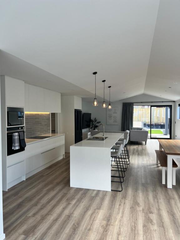 eine offene Küche und ein Wohnzimmer mit einer weißen Arbeitsplatte in der Unterkunft 3Bedroom 2Bathroom Golf Skiing Hiking Lake Mountains 7 Min To Airport in Queenstown