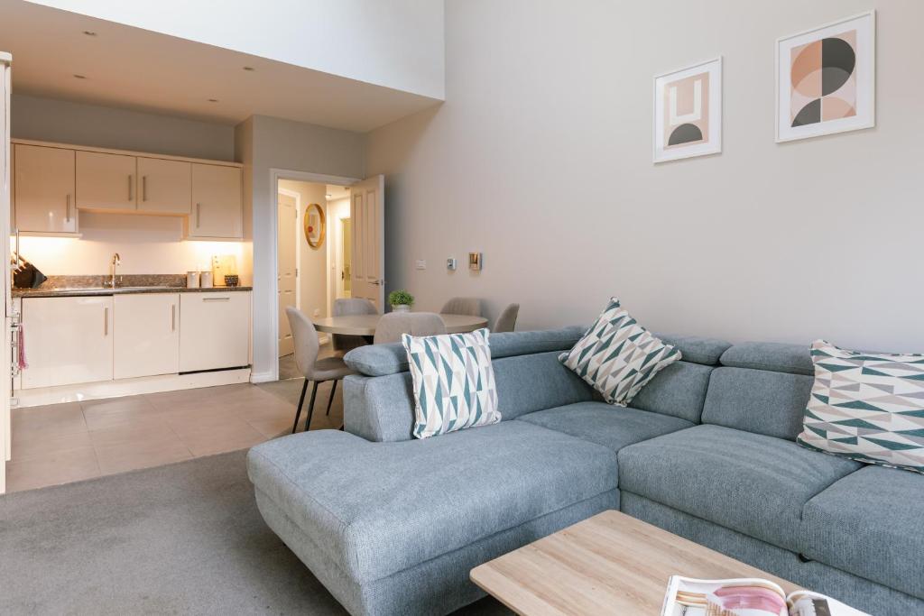 a living room with a blue couch and a kitchen at Chic 2-Bed, 2 Bath Apt in City Centre Sleeps 6, Free Secure Parking in Belfast