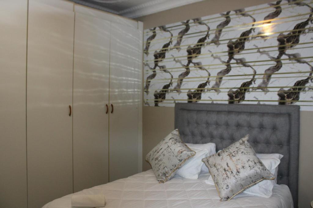 a bedroom with a bed with two pillows at Chic Guest House Alberton in Alberton