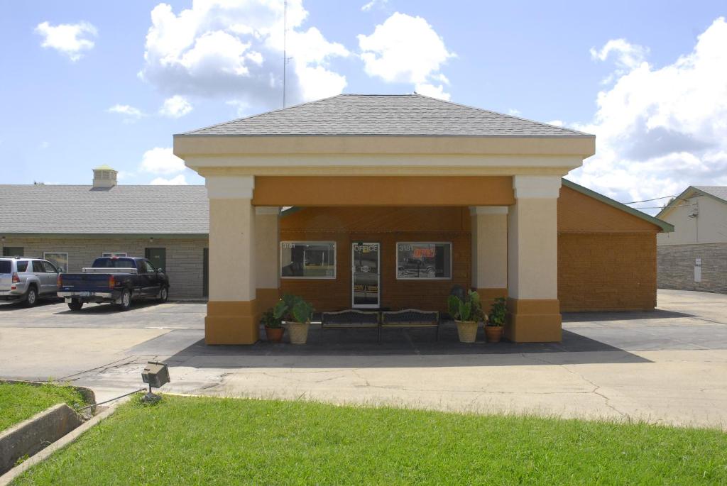 een gebouw met een veranda met een parkeerplaats bij America's Best Inn and Suites Emporia in Emporia