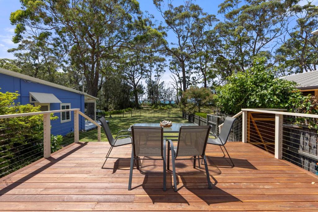 een houten terras met een tafel en stoelen erop bij Banksia Cottage - Pet Friendly Waterfront in Callala Bay
