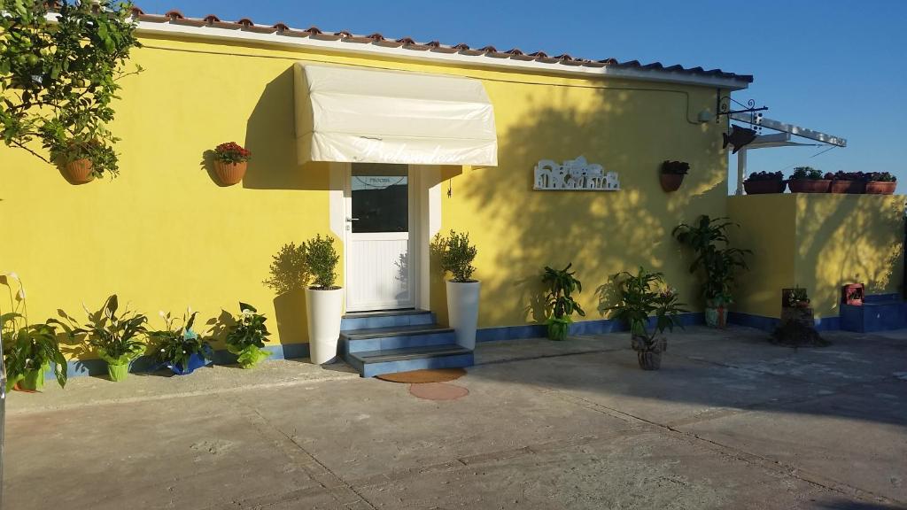 a yellow building with a white door and plants at Belvedere in Procida