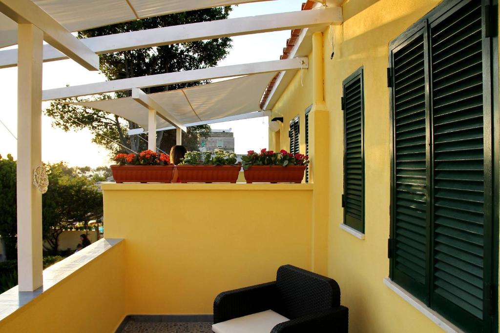 a balcony with a chair and flowers on a yellow wall at Belvedere in Procida