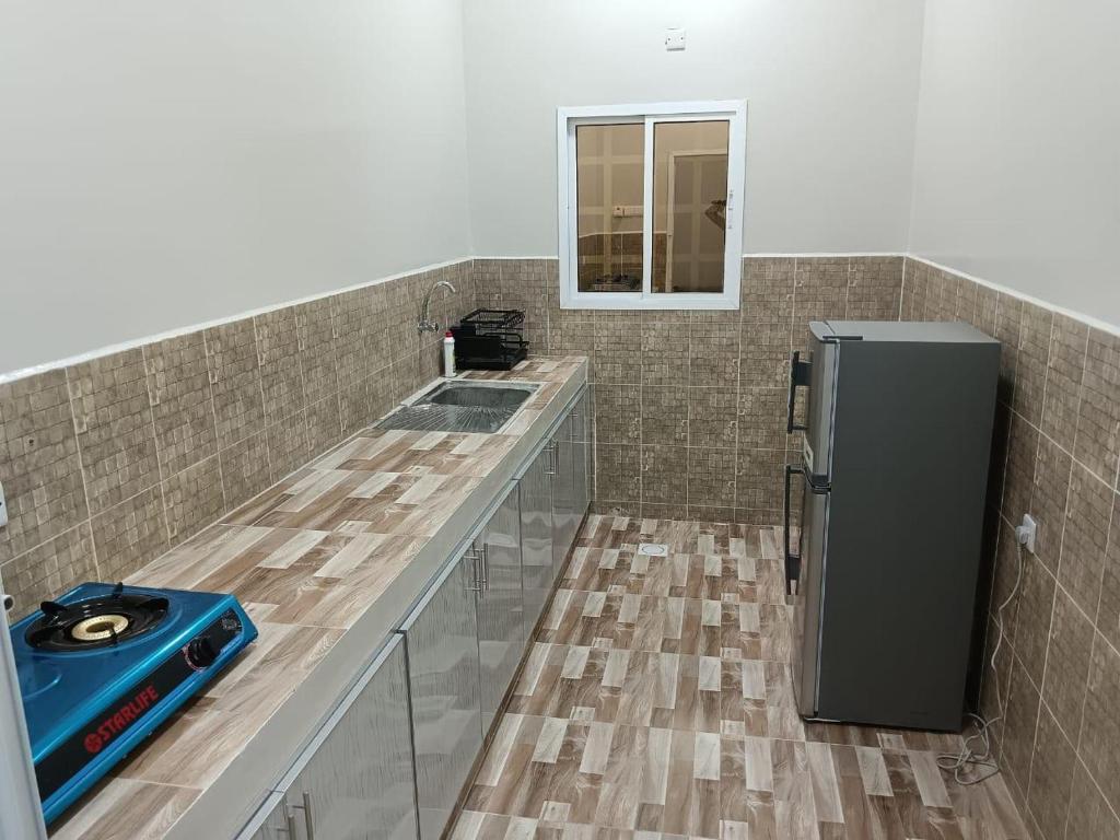 una cocina con encimera y refrigerador en ريف سناو للشقق الفندقية, en Distah