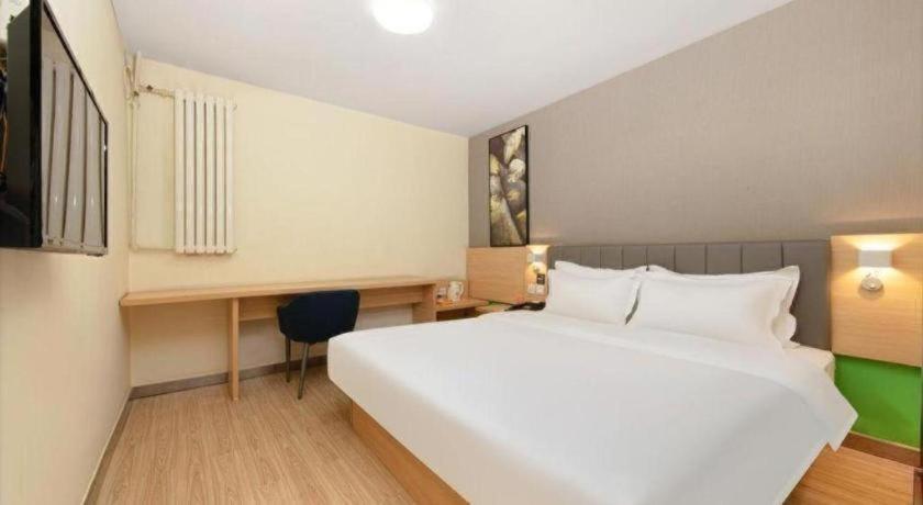 Un dormitorio con una gran cama blanca y un escritorio. en 7 Days Inn West Gate of Taiyuan University of Technology, en Taiyuán