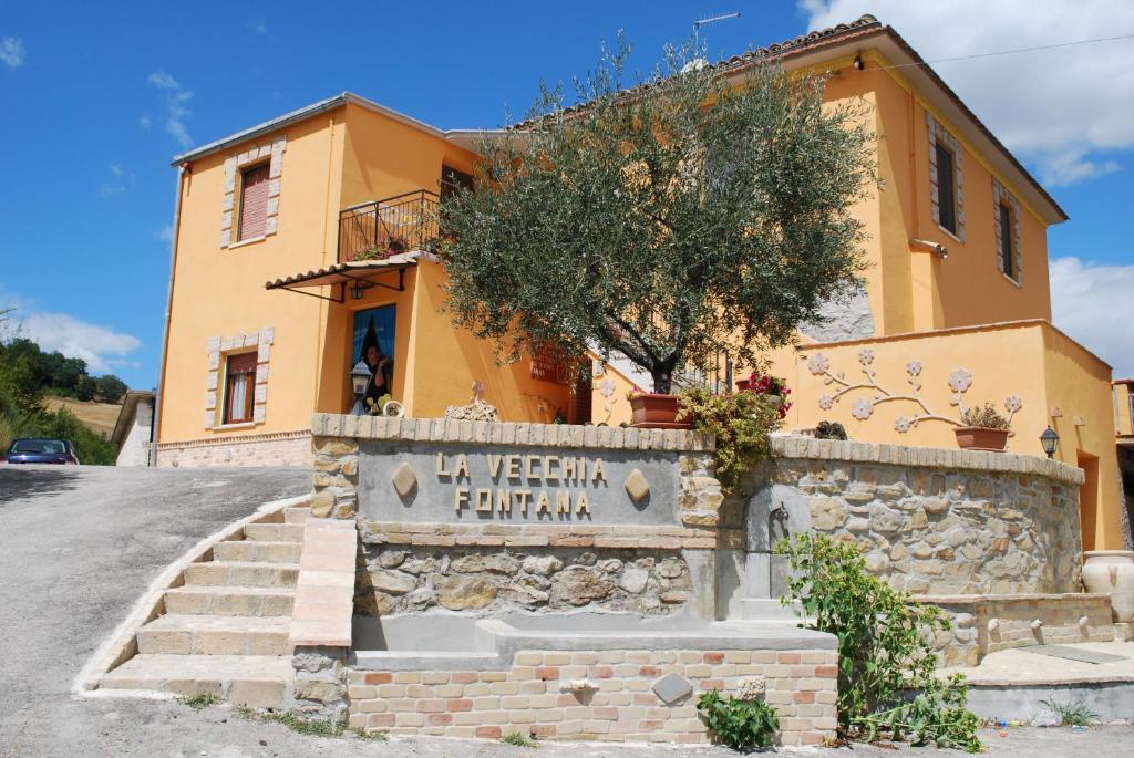 una casa amarilla con un cartel delante en Agriturismo La Vecchia Fontana, en Penne