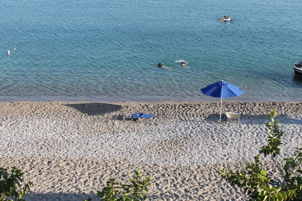 哈拉奇的住宿－Haraki Aqua Blue，海滩上摆放着蓝色的遮阳伞,人们在水中游泳