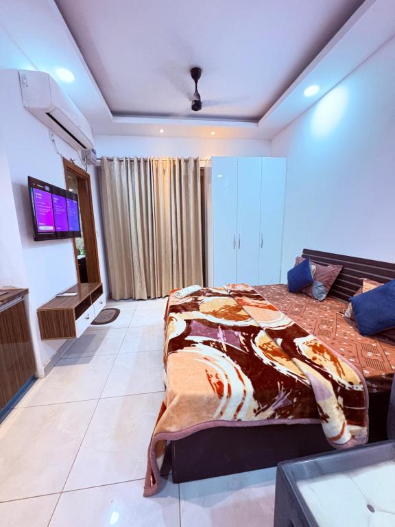 诺伊达Amigos Stays的一间卧室，里面有一张床和一台平板电视