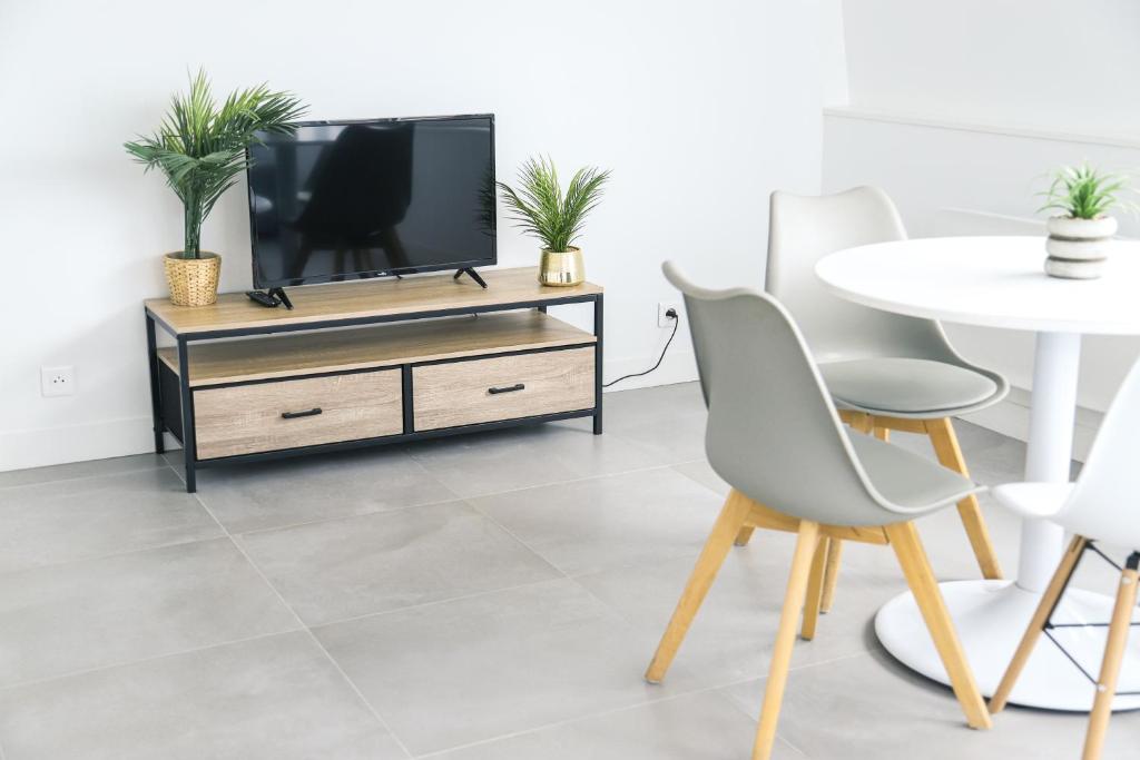Una sala de estar con un televisor y una mesa. en Le Magelan, en Vaires-sur-Marne