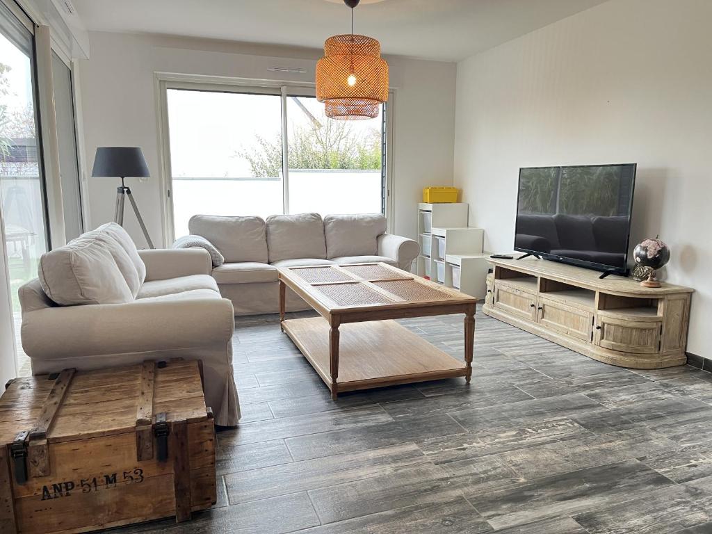 ein Wohnzimmer mit Sofa und Fernseher in der Unterkunft Le Virage du Circuit - Mulsanne in Mulsanne