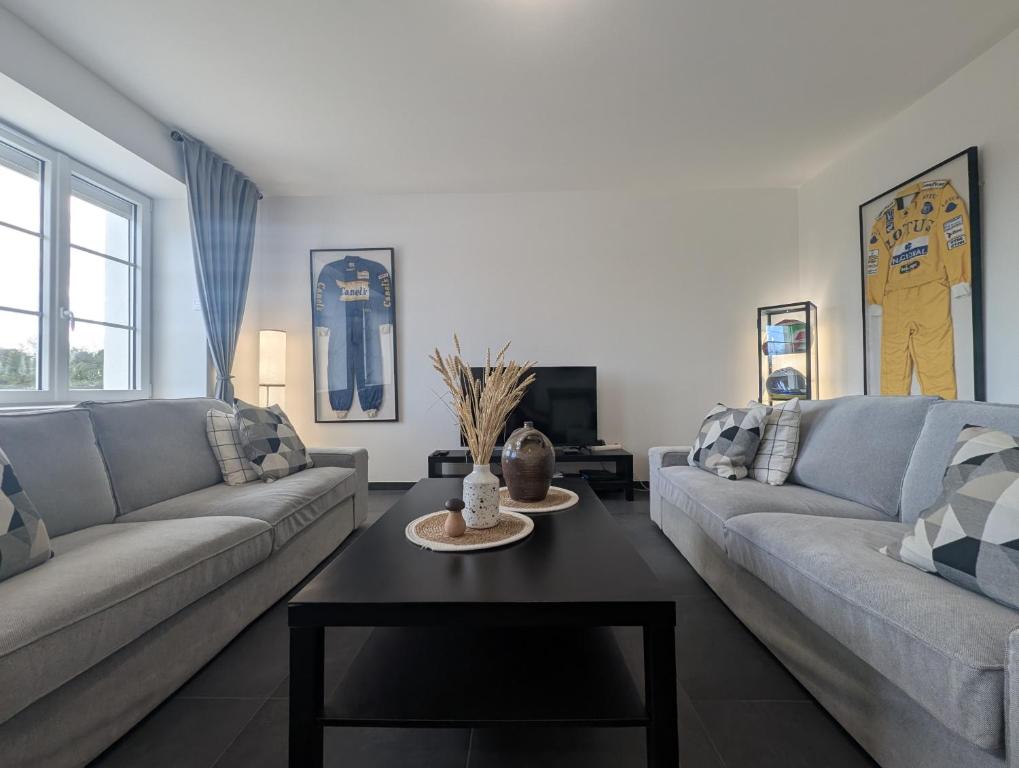 a living room with two couches and a table at La Maison des Vergers in Teloché