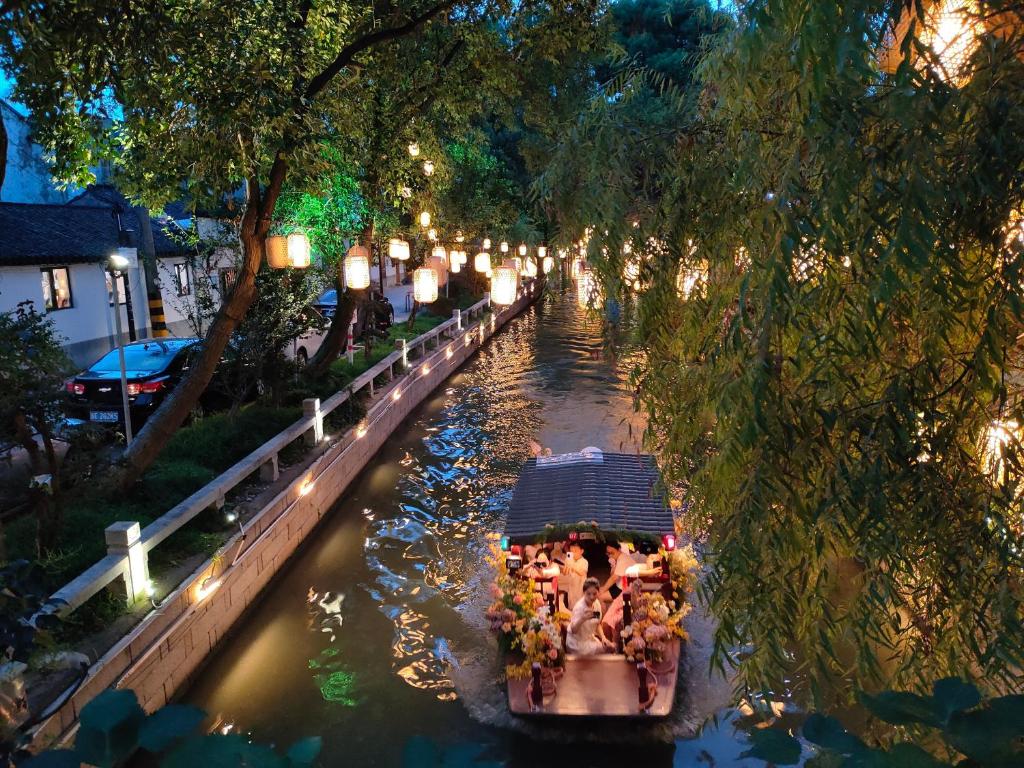 a boat traveling down a river with people in it at Luxury Riverside House with Garden in Central Suzhou in Suzhou
