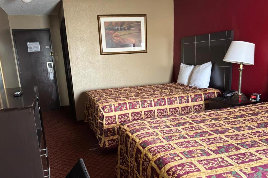 a hotel room with two beds and a lamp at Broadway INN & SUITES OKC in Oklahoma City