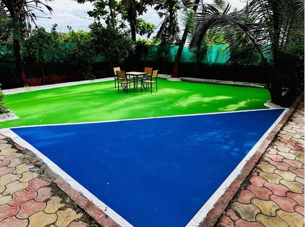 un sol bleu et vert avec une table et des chaises dessus dans l'établissement Cozy Madh Island Cottage with Private Courtyard, à Jāmb