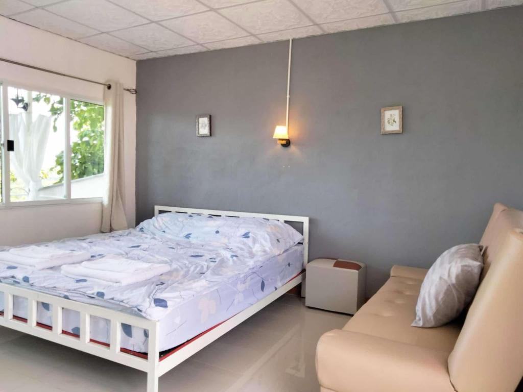 Ban Hin Hakบ้านสวนคึดฮอดโฮมสเตย์ ศรีสวัสดิ์ กาญจนบุรี的卧室里有一张白色的床和一张沙发