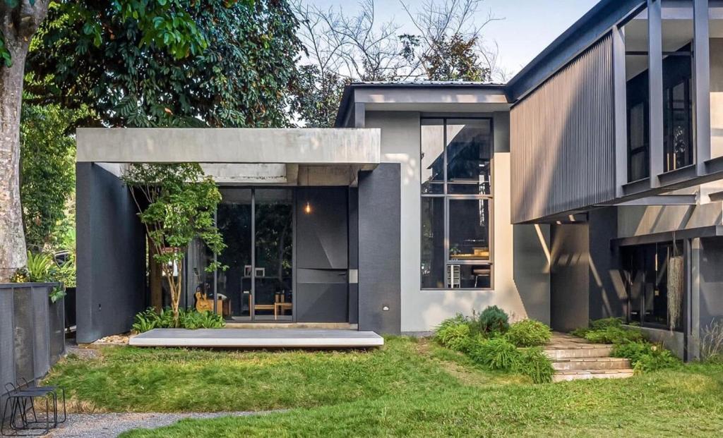 a gray house with glass doors and a yard at Moonstone Villa Chiang Mai in Chiang Mai