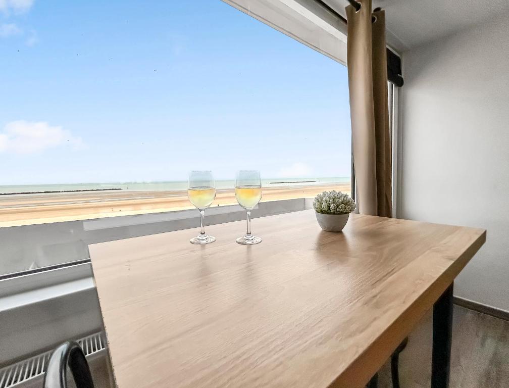 two glasses of wine sitting on a table in front of a window at Vue mer imprenable à Dunkerque, l'appel du large! in Dunkerque