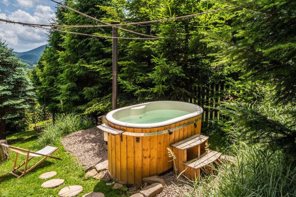 a wooden bath tub in a yard with trees at Alemiło - uroczy dom z balią i widokiem na Babią Górę in Zawoja