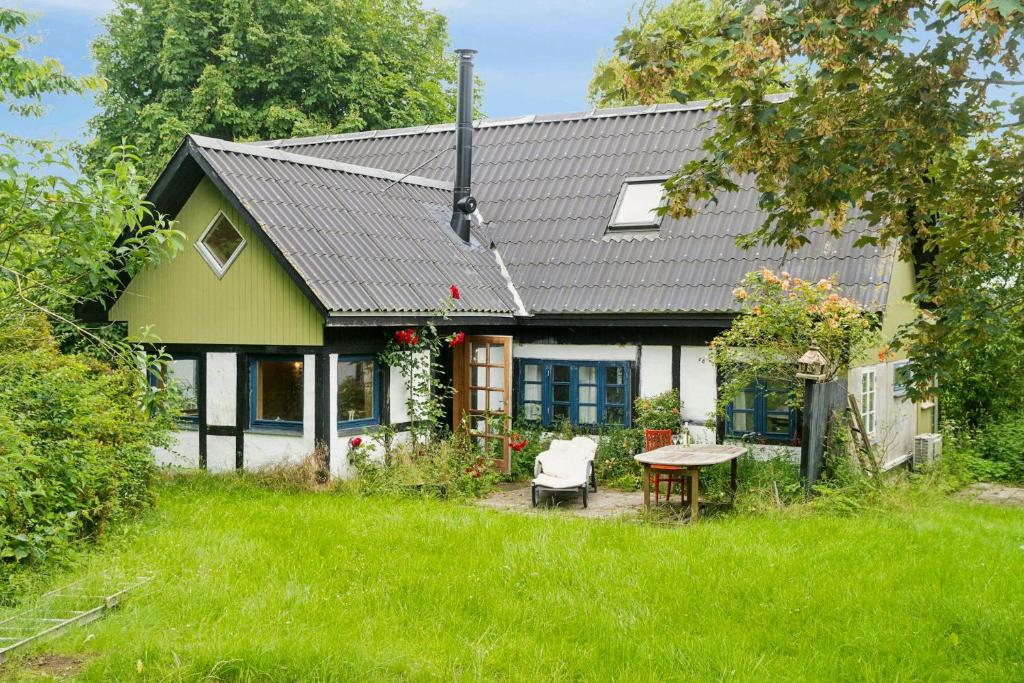 a green and white house with a table in the yard at Quiet Hideaway Surrounded By Nature in Vesterborg