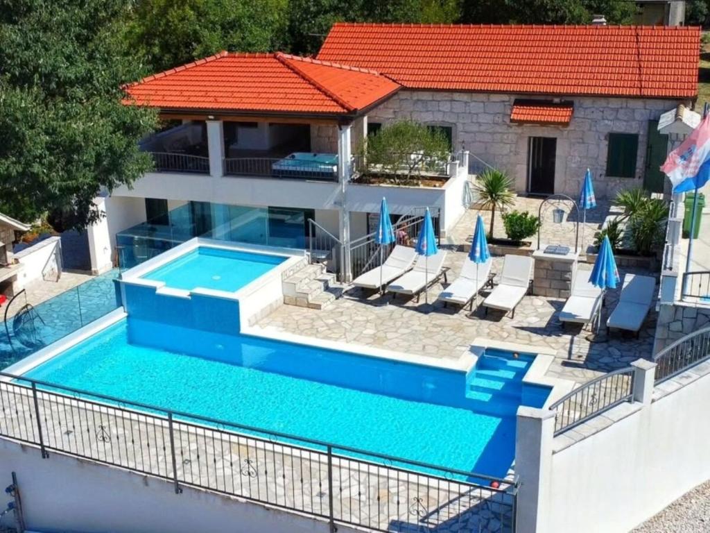 een zwembad met stoelen en een huis bij Dvori Stipanovi with heated pool and jacuzzi in Donje Rašćane
