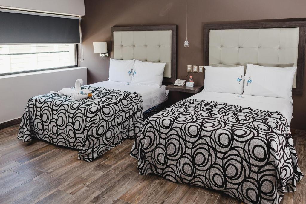 una habitación de hotel con 2 camas y una mesa con un animal de peluche. en Hotel Flamingo Merida, en Mérida