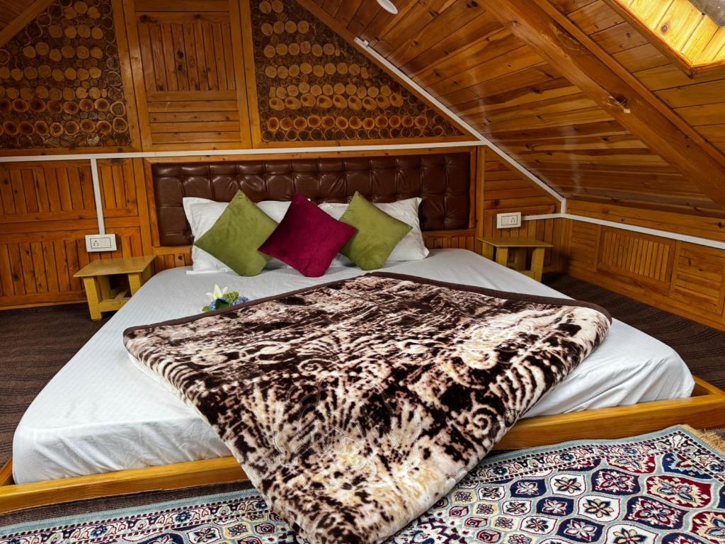 a bedroom with a bed with a blanket on it at Himalayan Pine Majesty in Jibhi