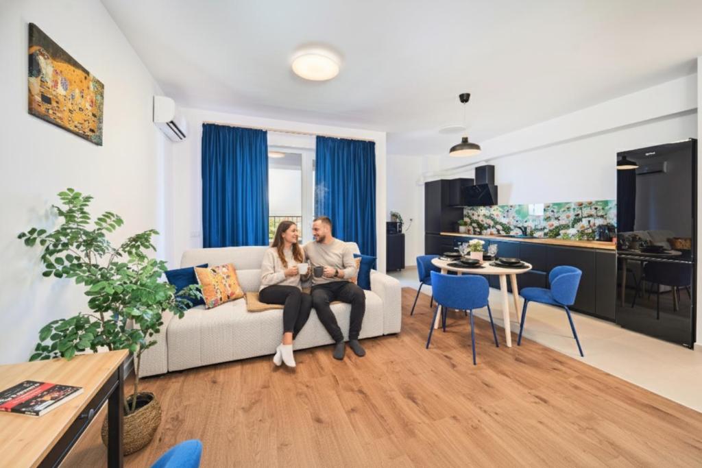 a man and woman sitting on a couch in a living room at Sunset view Central Tudor apartment - by Open House in Timişoara