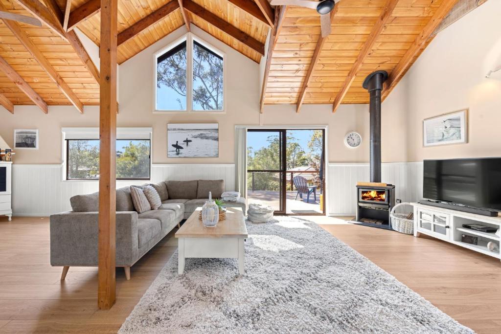 a living room with a couch and a tv at Holiday Retreat Jervis Bay - 5 Min Walk to Bay in Callala Bay