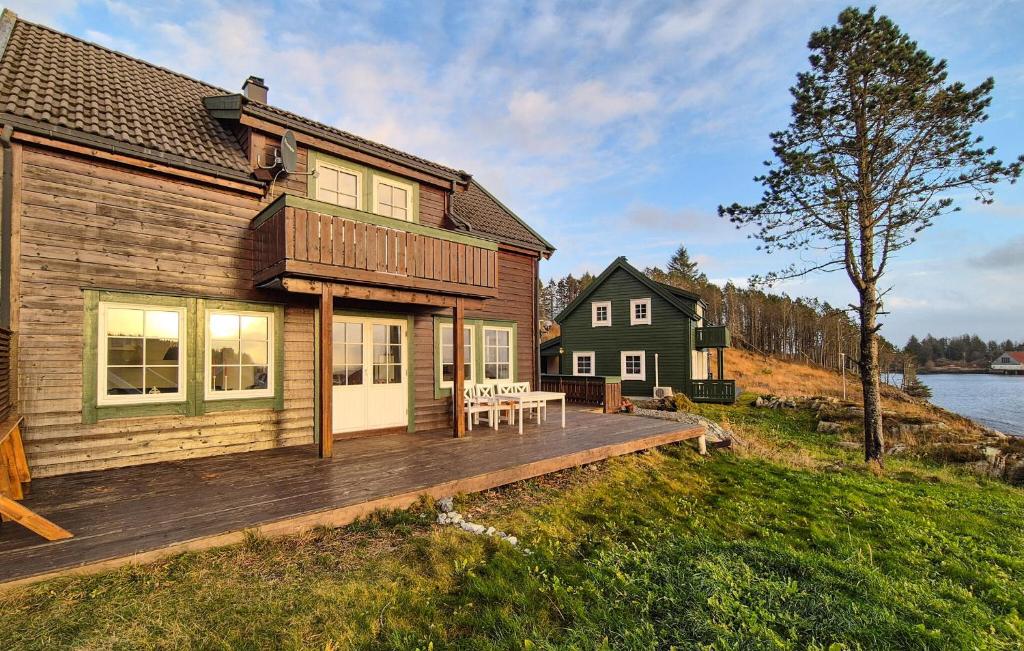 a house with a wooden deck next to the water at Beautiful Home In Bøvågen With Sauna in Otterholmen