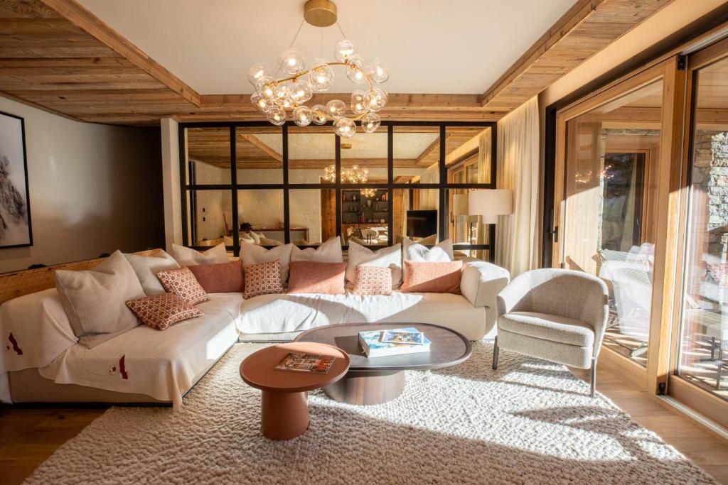 a living room with a white couch and a chandelier at Antarès URSA 303 - luxury apartment ski inski out in Méribel