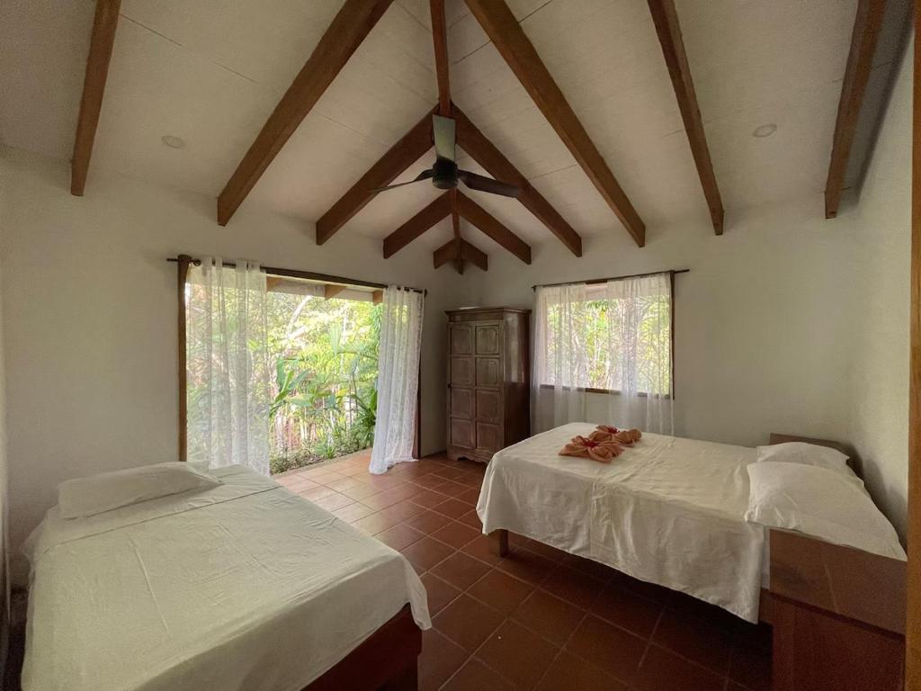 a bedroom with two beds and a ceiling fan at Hidden Coast villa Frangipani Ocean & Jungle in Manzanillo