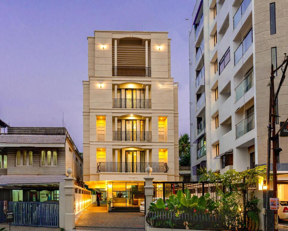 un edificio blanco alto con luces encendidas en Saravana Grand Suites, en Kochi
