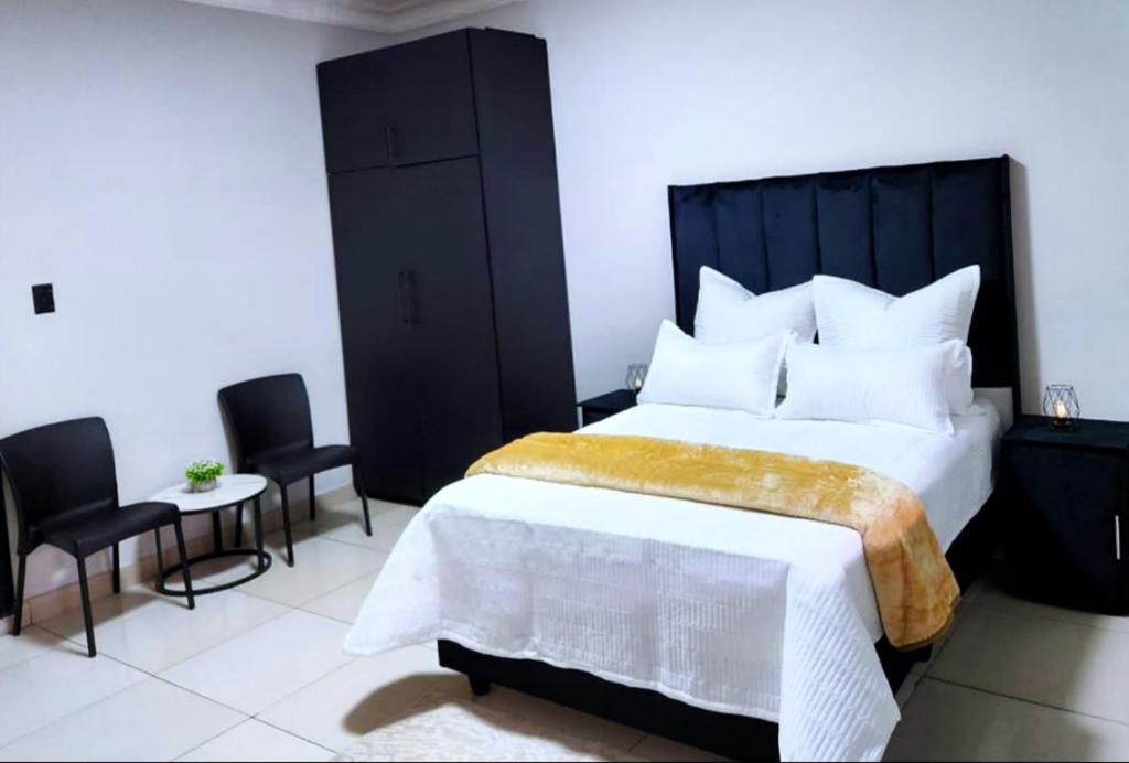 a bedroom with a large bed and two chairs at WinHaven Guest House in Randfontein