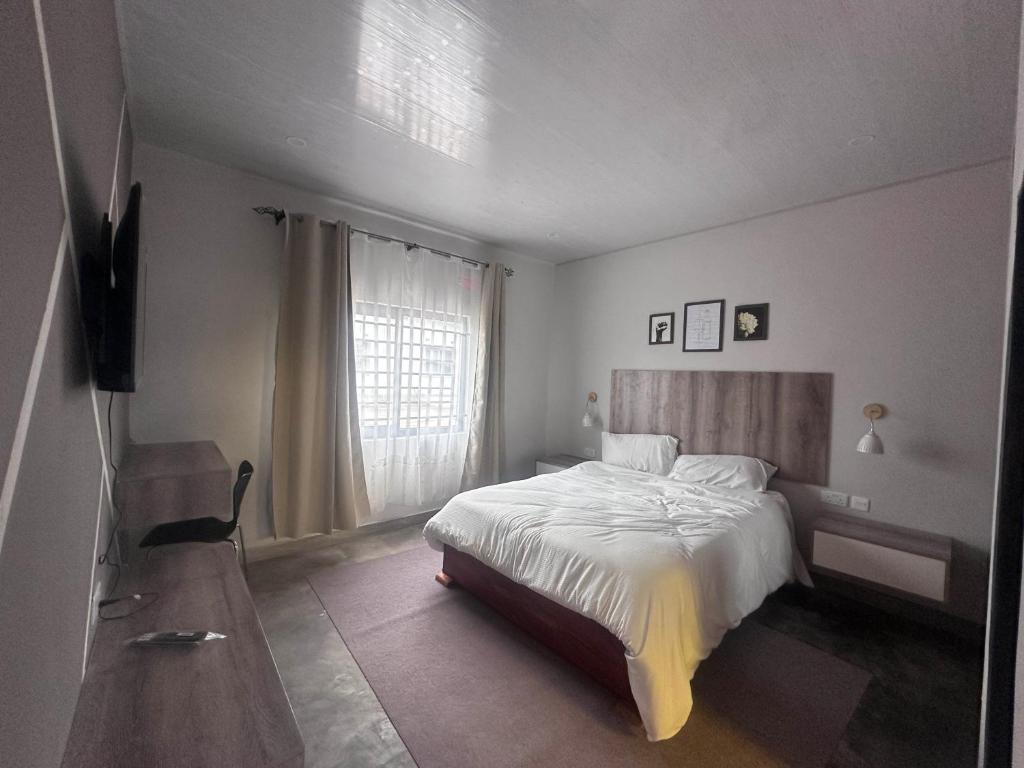 a bedroom with a bed and a television and a window at Zango Apartments in Shikalenge