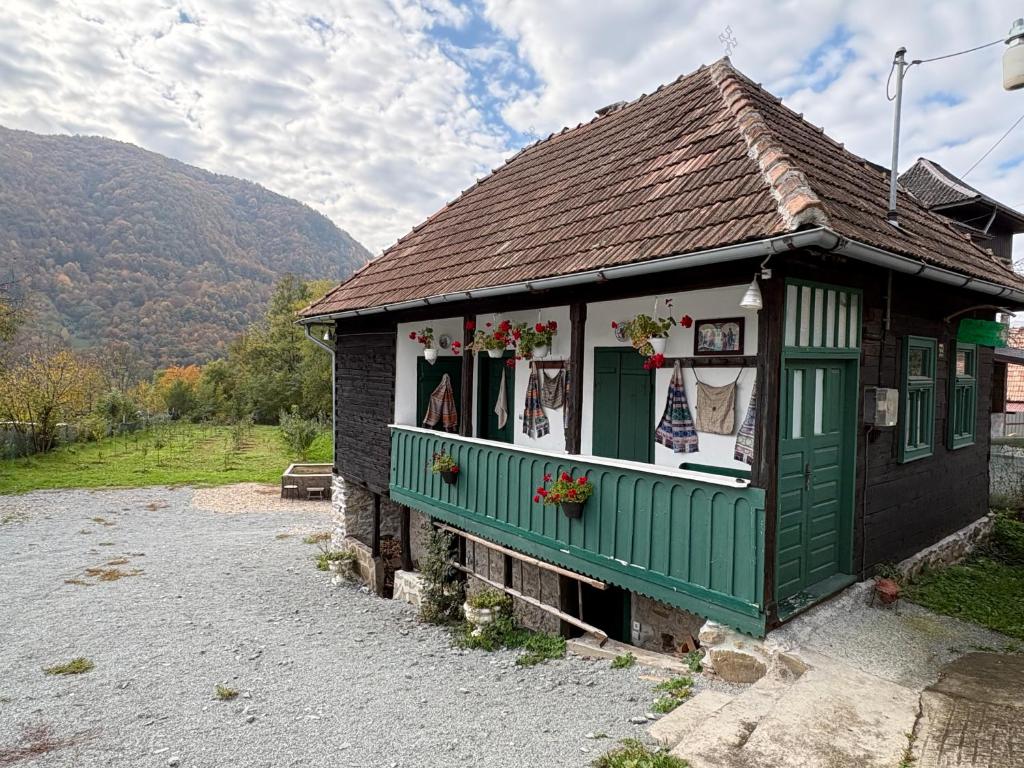 a small house with green trim and flowers in the window at Casa Verde in Lupşa