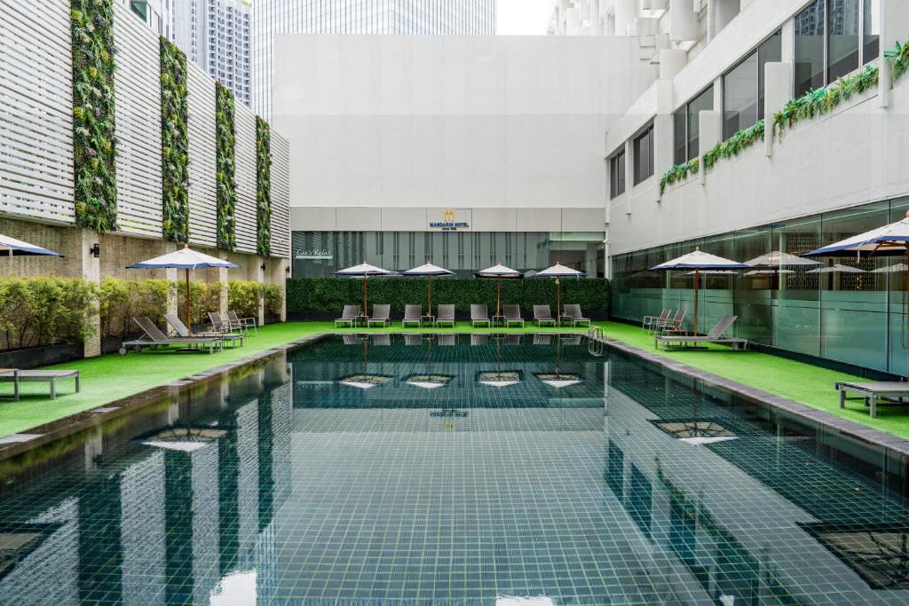 a pool in the middle of a building with tables and umbrellas at Mandarin Hotel Managed by Centre Point in Bangkok