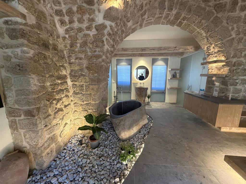 a stone bathroom with a tub in a stone wall at Akotika boutique in Acre