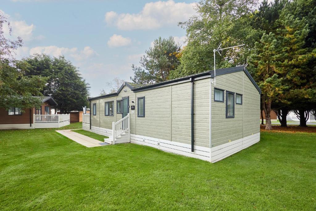 une petite maison dans une cour avec un champ d'herbe dans l'établissement Reynards Retreat Lodge with Hot Tub, à Barmby on the Moor