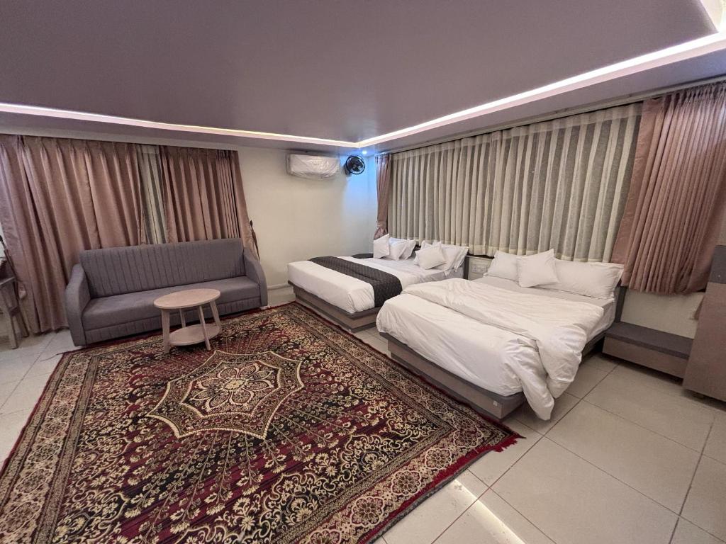 Una habitación de hotel con dos camas, un sofá y una alfombra. en NR Hotel, en Rīngas