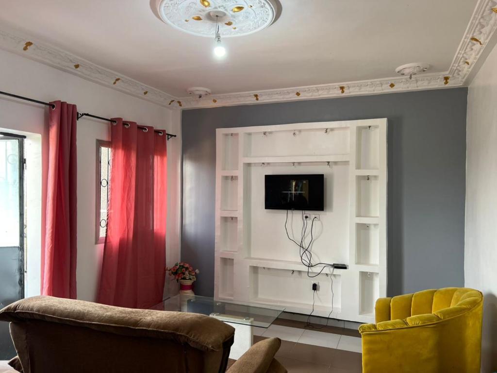 a living room with red curtains and a tv on a wall at Janamaev in Yaoundé