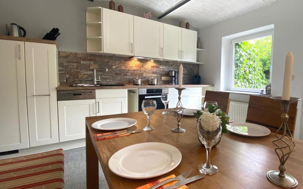 a kitchen with a wooden table with plates and wine glasses at Ferienhaus "Am Papststein" in Papstdorf