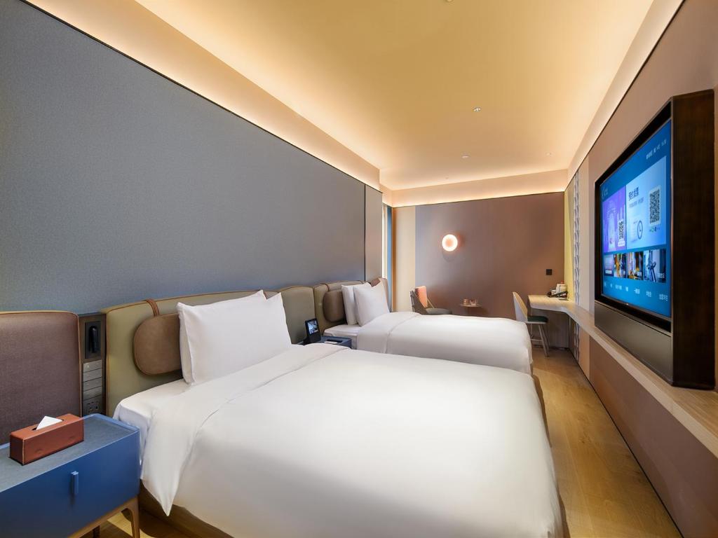 ein Schlafzimmer mit zwei Betten und einem Flachbildfernseher in der Unterkunft Orange Hotel Shanghai New International Expo Centre in Shanghai