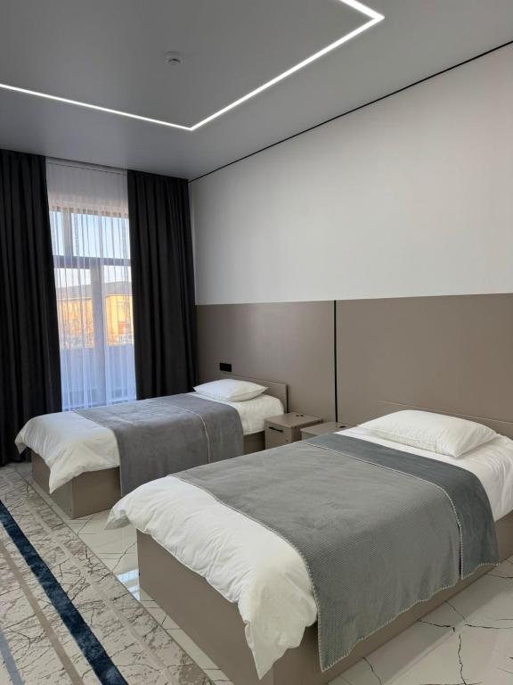 a bedroom with two beds and a large window at Отель Жанатас in Zhangatas