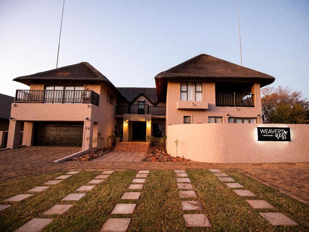 a large house with a yard in front of it at Weavers Nest Guesthouse in Modimolle